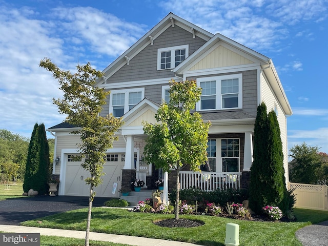 craftsman inspired home featuring a porch, a garage, and a front yard