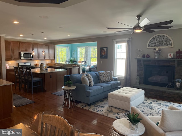 living room with a fireplace, ceiling fan, dark wood-type flooring, and sink