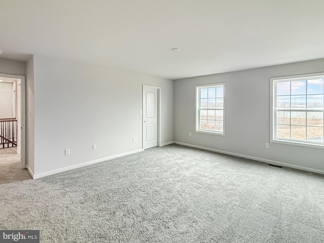 carpeted spare room with visible vents and baseboards