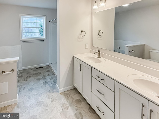 bathroom featuring double vanity, baseboards, and a sink