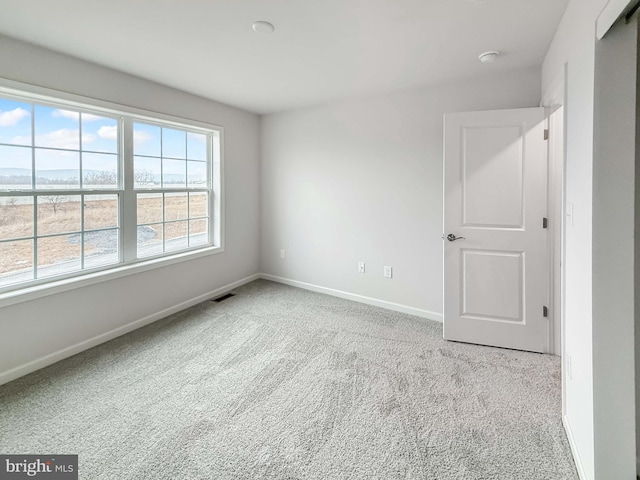 carpeted empty room with visible vents and baseboards