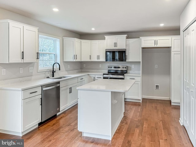 kitchen featuring light wood-style flooring, recessed lighting, a sink, stainless steel appliances, and white cabinetry