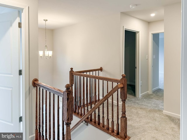 stairway with carpet flooring, baseboards, and an inviting chandelier