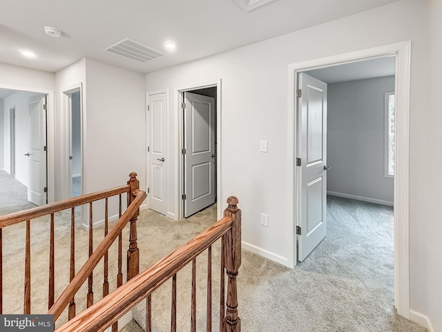 corridor featuring light colored carpet, an upstairs landing, visible vents, and baseboards