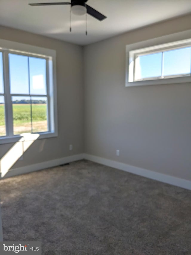 carpeted spare room with baseboards and a ceiling fan