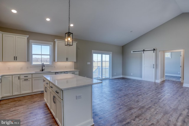 kitchen featuring a center island, light countertops, a barn door, wood finished floors, and a sink