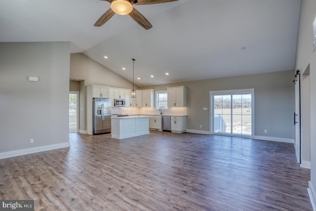 kitchen with appliances with stainless steel finishes, open floor plan, a center island, and white cabinets