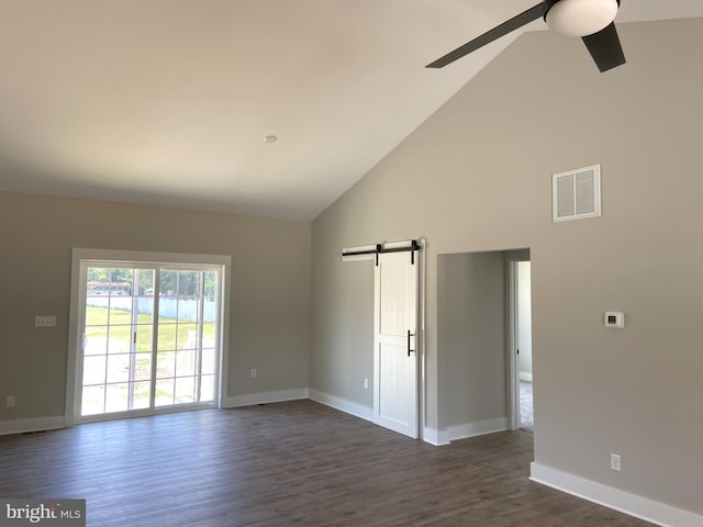 spare room with a barn door, ceiling fan, high vaulted ceiling, and dark wood-type flooring