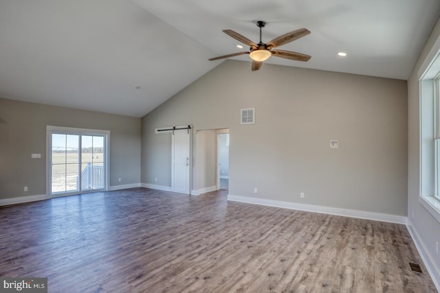 empty room with a barn door, visible vents, and wood finished floors