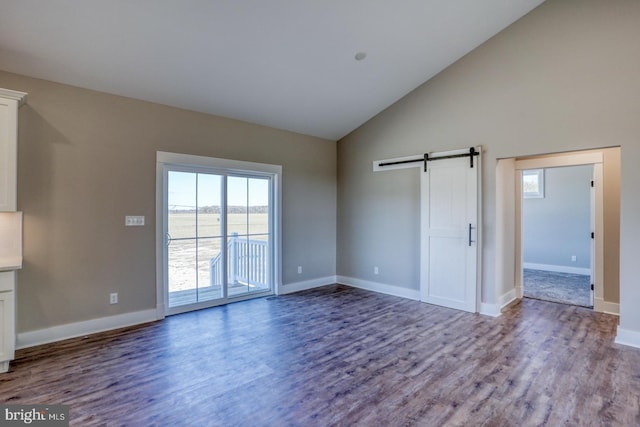 interior space featuring a barn door, baseboards, high vaulted ceiling, and wood finished floors