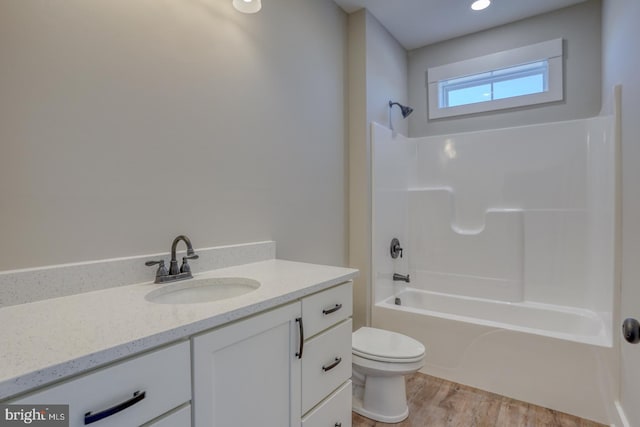 full bath featuring washtub / shower combination, toilet, vanity, and wood finished floors