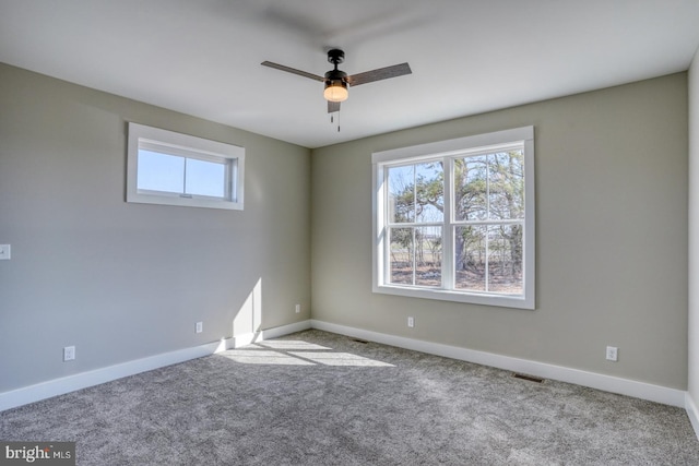 carpeted spare room featuring visible vents, ceiling fan, and baseboards