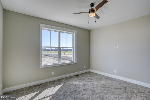 unfurnished room featuring carpet flooring, baseboards, visible vents, and ceiling fan