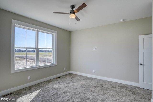 carpeted empty room with visible vents, baseboards, and a ceiling fan