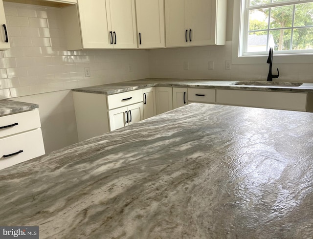 kitchen with white cabinets, backsplash, and sink