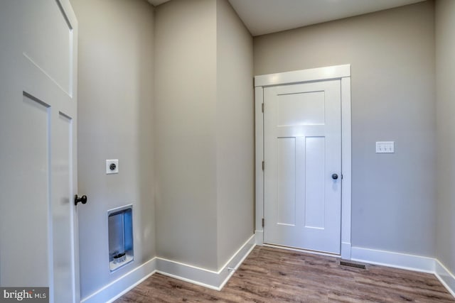 clothes washing area with wood finished floors, baseboards, hookup for an electric dryer, visible vents, and laundry area