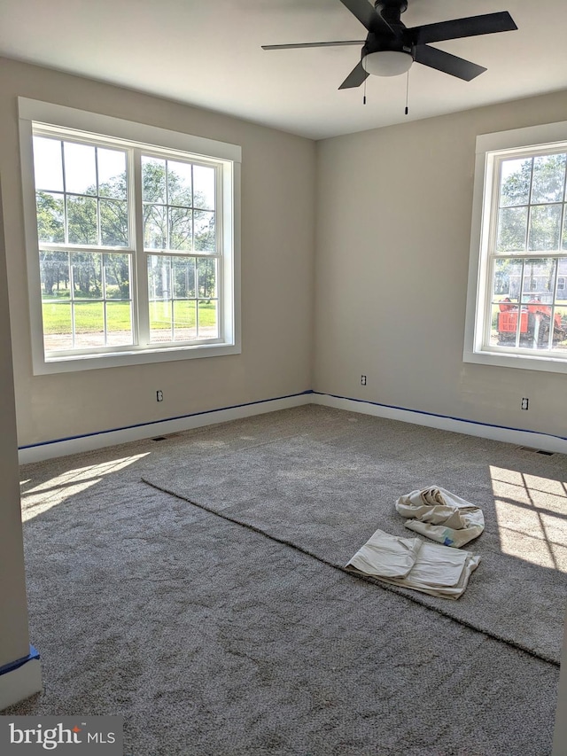 carpeted spare room with ceiling fan and plenty of natural light