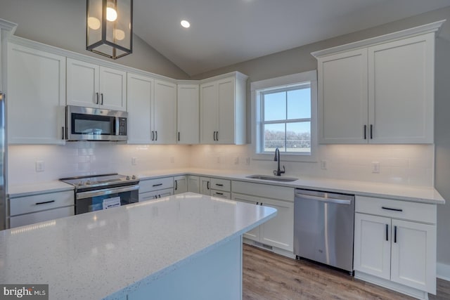 kitchen featuring a sink, decorative backsplash, vaulted ceiling, white cabinets, and appliances with stainless steel finishes