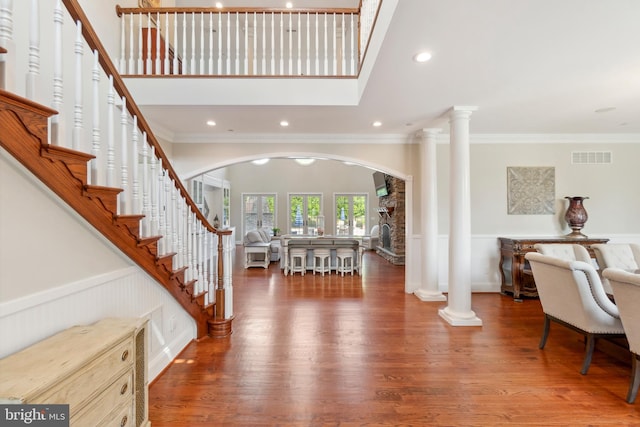 entrance foyer featuring a high ceiling, hardwood / wood-style floors, ornamental molding, and ornate columns