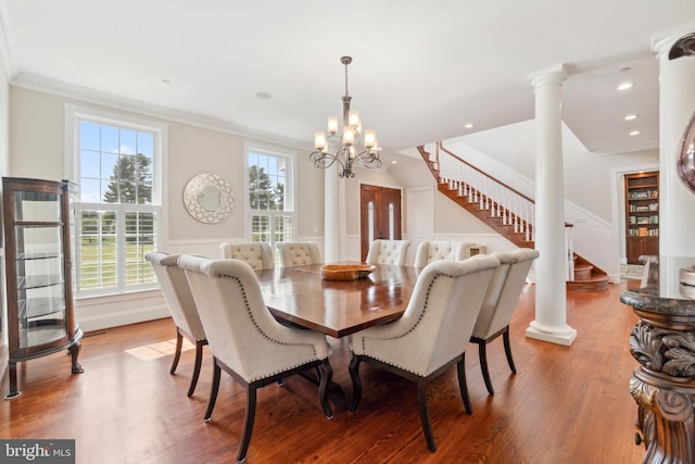 dining space with decorative columns, hardwood / wood-style flooring, a chandelier, and a healthy amount of sunlight