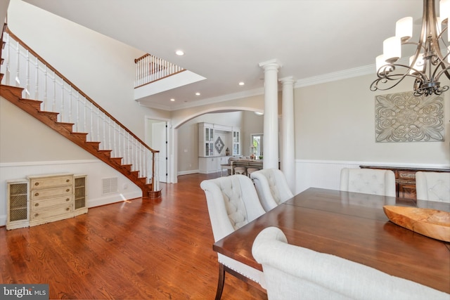 dining space featuring ornamental molding, dark hardwood / wood-style floors, a notable chandelier, and ornate columns