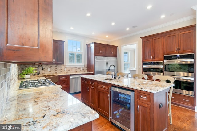 kitchen with appliances with stainless steel finishes, a wealth of natural light, an island with sink, and wine cooler