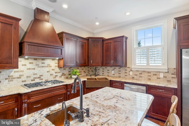 kitchen with backsplash, sink, light stone countertops, appliances with stainless steel finishes, and custom range hood