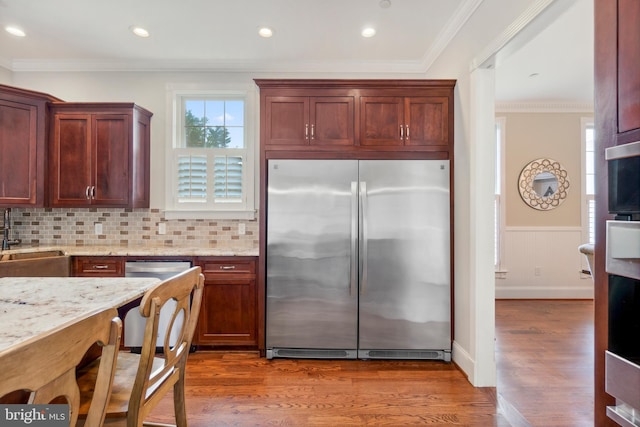 kitchen with light stone counters, stainless steel appliances, dark hardwood / wood-style flooring, sink, and ornamental molding