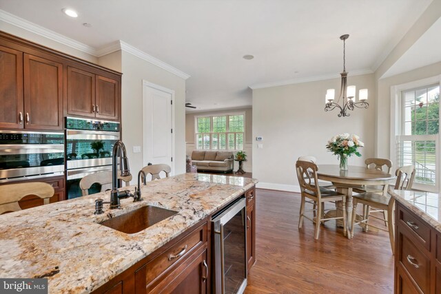 kitchen featuring hanging light fixtures, hardwood / wood-style floors, a chandelier, sink, and wine cooler