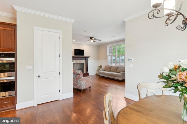 dining space featuring ceiling fan with notable chandelier, crown molding, and dark hardwood / wood-style floors