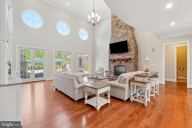 living room featuring crown molding, wood-type flooring, french doors, and a fireplace