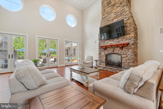 living room with a fireplace, hardwood / wood-style floors, french doors, ornamental molding, and a high ceiling