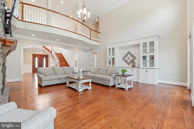 living room with light hardwood / wood-style flooring, a fireplace, an inviting chandelier, and a towering ceiling