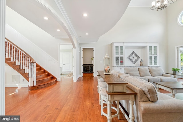 living room featuring crown molding, an inviting chandelier, and light hardwood / wood-style floors