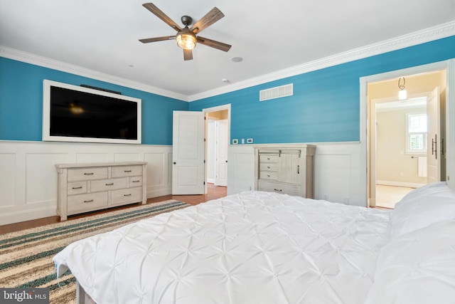 bedroom featuring light wood-type flooring, ceiling fan, ensuite bath, and ornamental molding