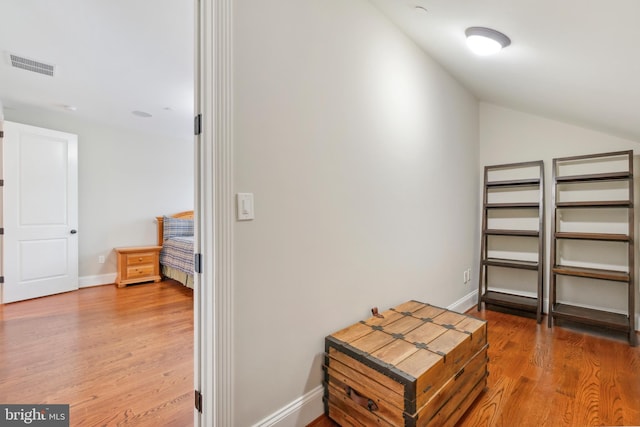 hallway with vaulted ceiling and wood-type flooring