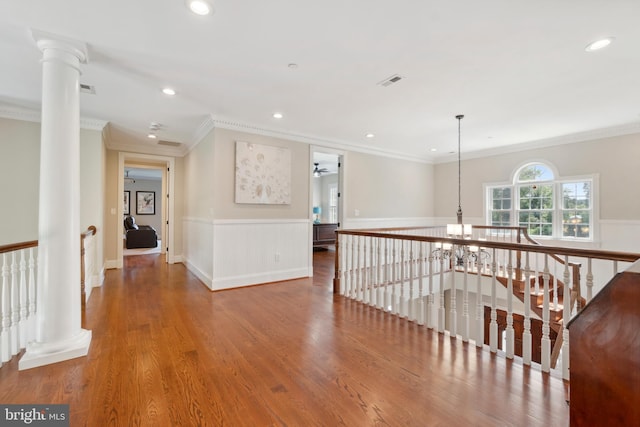 hallway featuring crown molding, hardwood / wood-style floors, and decorative columns