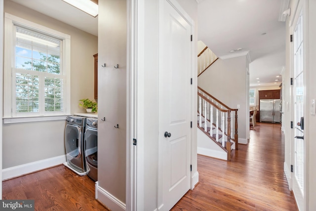 clothes washing area featuring separate washer and dryer, dark wood-type flooring, and crown molding