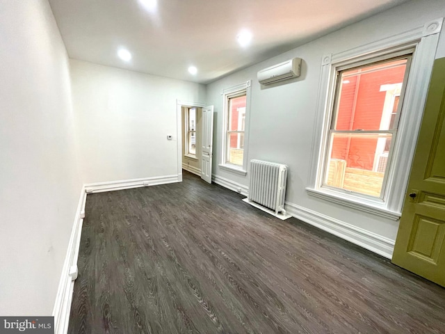 spare room featuring radiator, dark hardwood / wood-style flooring, and a wall unit AC