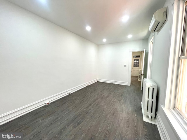 empty room with radiator heating unit, dark hardwood / wood-style flooring, and a wall mounted AC