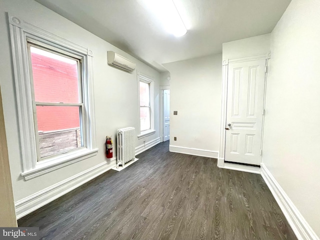 interior space featuring radiator heating unit, dark hardwood / wood-style flooring, and an AC wall unit