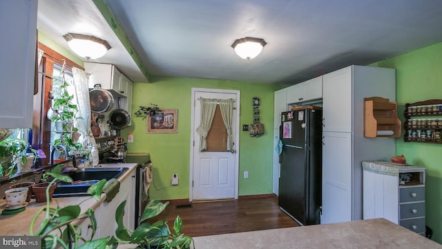 kitchen featuring dark hardwood / wood-style flooring, sink, white cabinetry, black refrigerator, and electric stove