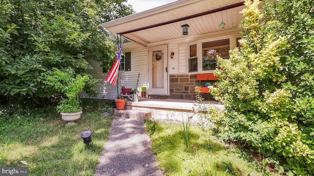 doorway to property featuring stone siding and covered porch