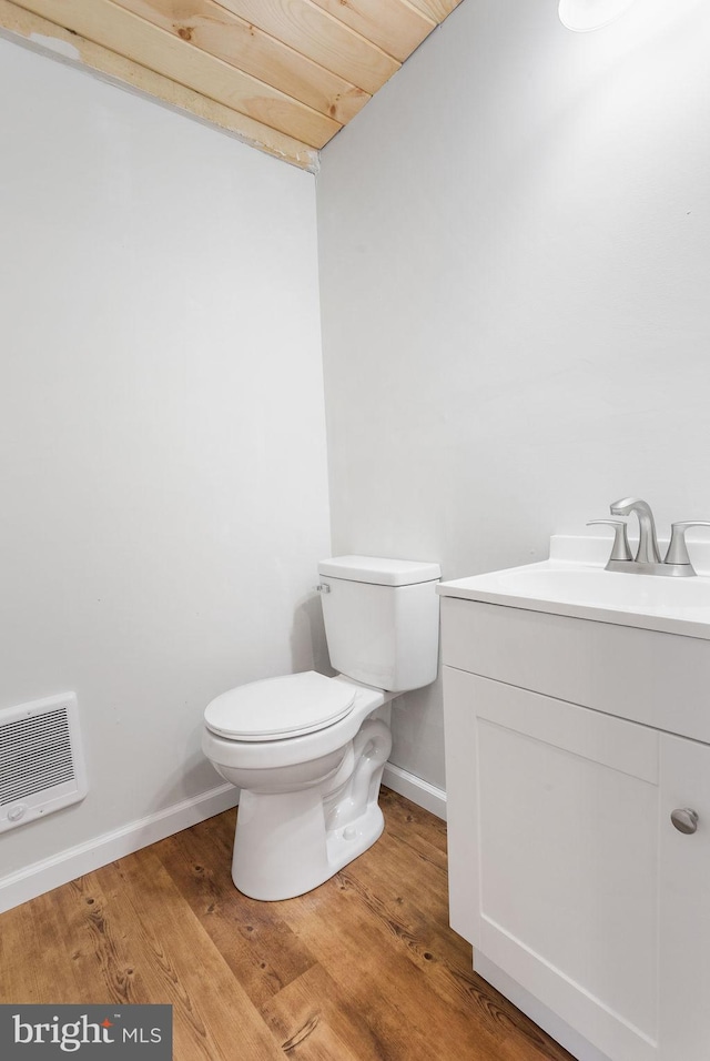 bathroom with wooden ceiling, heating unit, hardwood / wood-style floors, toilet, and vanity