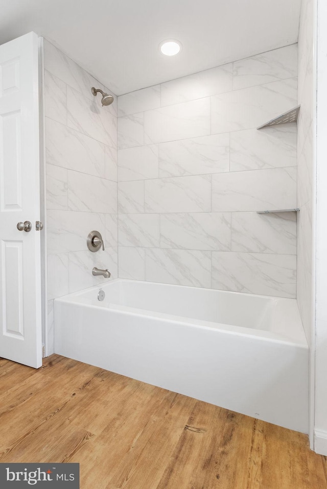 bathroom with hardwood / wood-style floors and tiled shower / bath