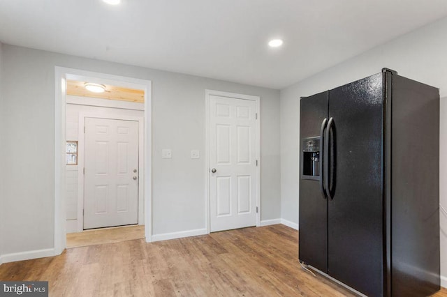 kitchen featuring black refrigerator with ice dispenser and light hardwood / wood-style flooring