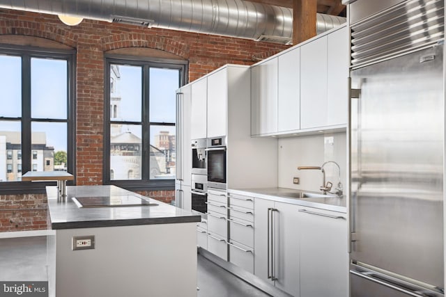 kitchen with plenty of natural light, brick wall, stainless steel appliances, and white cabinets