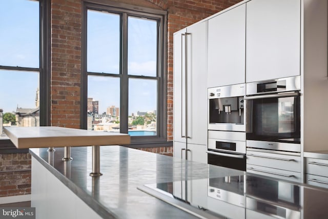 kitchen with white cabinetry, brick wall, and double oven