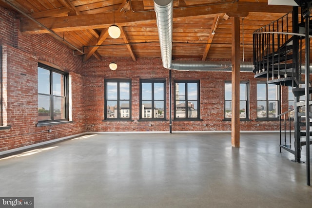 interior space with vaulted ceiling with beams, wooden ceiling, and brick wall