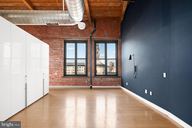 unfurnished bedroom featuring wood ceiling, brick wall, light hardwood / wood-style flooring, and beam ceiling